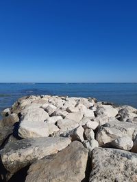 Rocks on beach against clear blue sky