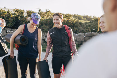 Happy women carrying exercise mats during group training session