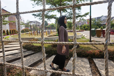 Rear view of woman sitting at park against sky