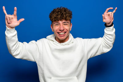 Portrait of smiling man gesturing against blue background