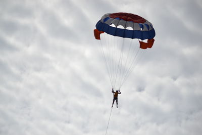 Low angle view of person parasailing against sky