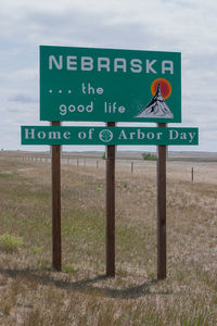 Close-up of road sign on field against sky