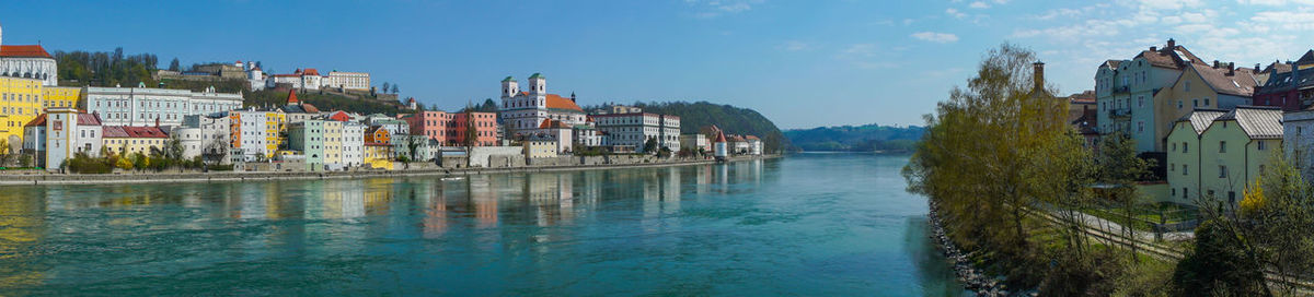 Buildings by river in town against sky