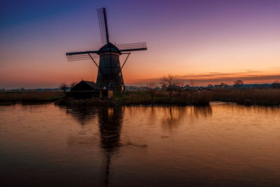 Traditional windmill on field during sunset