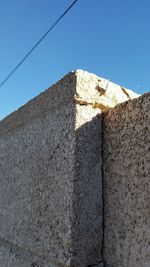 Low angle view of wall against clear blue sky