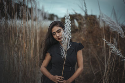 Portrait of woman standing by plants on field