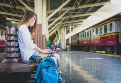 Side view of young woman sitting on book