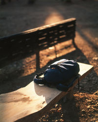 High angle view of backpack on wooden bench during sunset