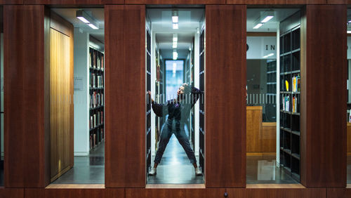 Reflection of young woman standing on glass at library