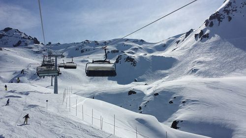 Ski lift over snowcapped mountains against sky