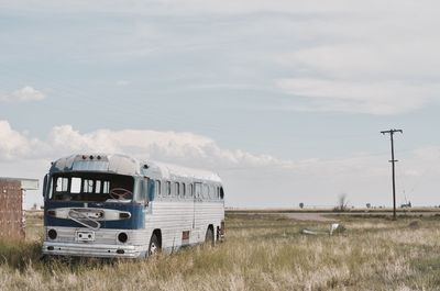 Abandoned bus on landscape against sky