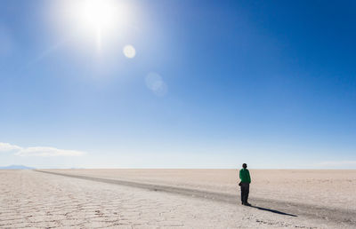 Rear view of man on desert against sky during sunny day
