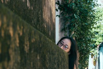 Portrait of woman standing behind weathered wall