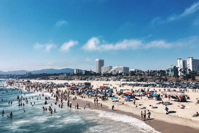 People enjoying at beach against blue sky