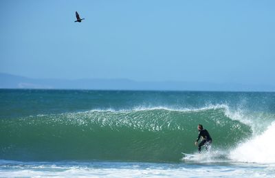 Man surfing in sea against clear sky