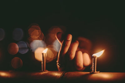 Cropped hand of woman with illuminated candles