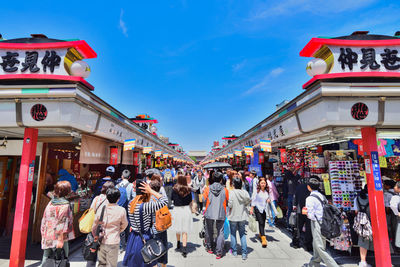 People walking in market against sky in city