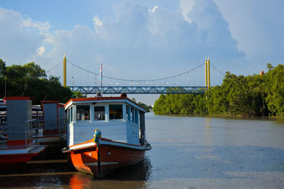 Boat on bridge over river against sky