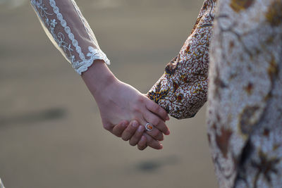 Midsection of couple holding hands 