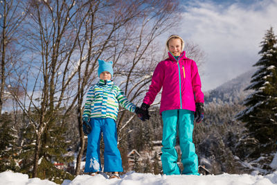 Full length of children on snow covered trees