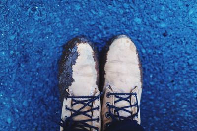 Low section of person with dirty shoes standing on road