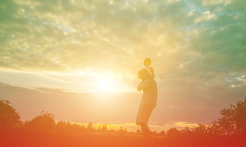 Man standing on field against sky during sunset