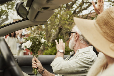 Man waving while sitting in convertible car