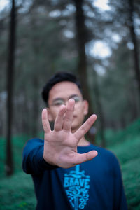 Portrait of young man gesturing at forest