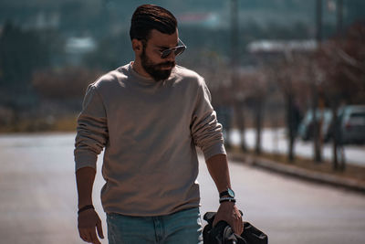 Young man looking away while standing on street in city