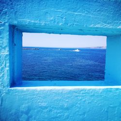 Close-up of sea against blue sky seen through window