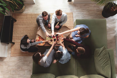 High angle view of friends sitting on sofa at home