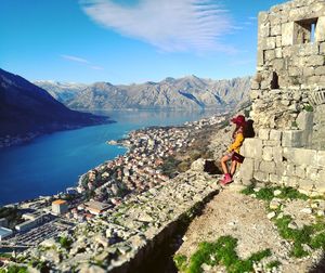 Woman standing against lake by mountains