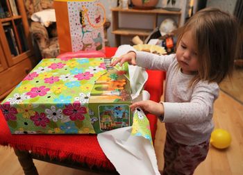 Cute girl opening gift at home