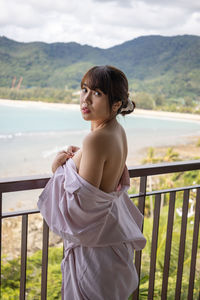 Woman standing on railing against mountain