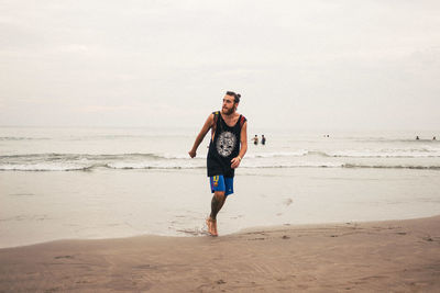 Full length of young man tourist walking at beach