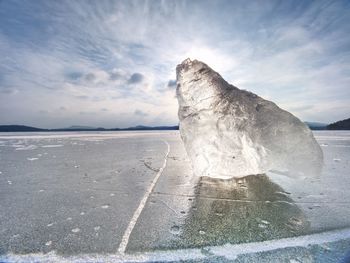 Drifting piece of iceberg and sun glaring on thick ice cover. drifting ice floes on river.