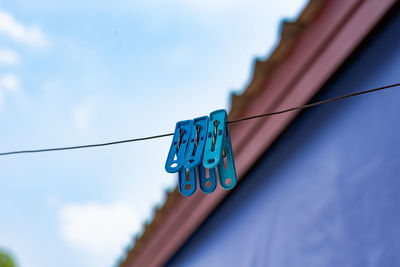 Low angle view of clothes hanging on rope against blue sky