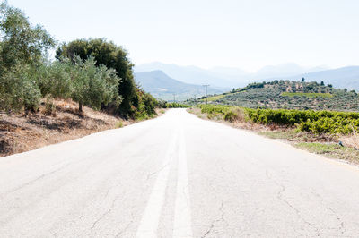 Road amidst trees against clear sky