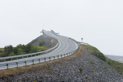 Road leading towards mountain against clear sky