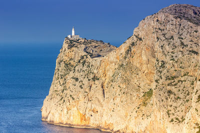 Scenic view of sea and mountain against clear blue sky