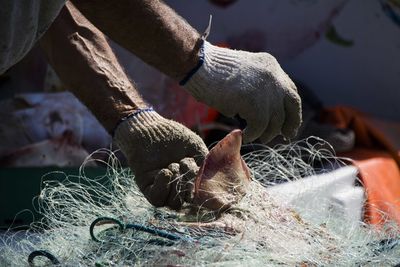 Cropped image of fisherman removing fish from net