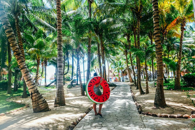 Rear view of woman carrying inflatable ring while walking on footpath