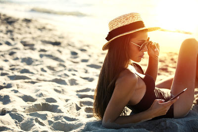 Young woman sitting on sand at beach