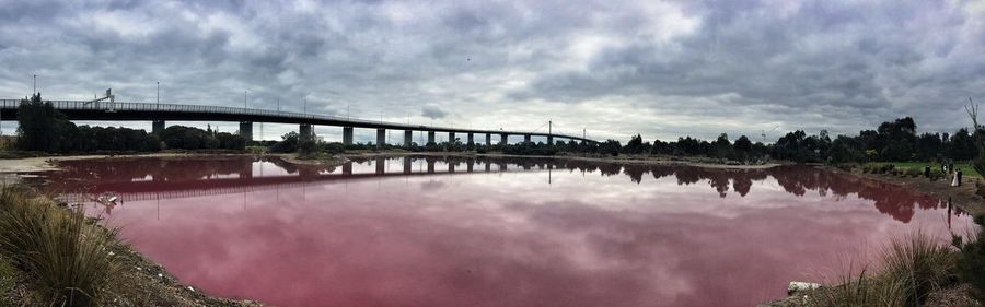 Bridge over river against cloudy sky