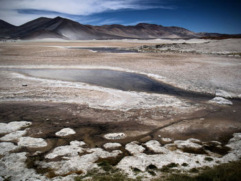 Scenic view of desert against cloudy sky