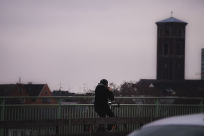 Side view of man bicycling against the church