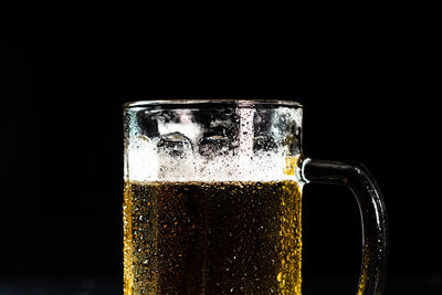 Close-up of beer glass against black background