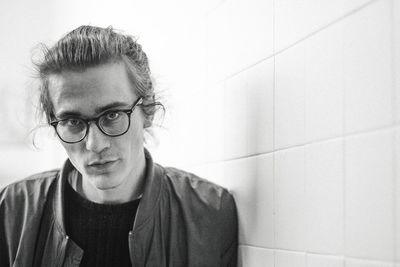 Portrait of young man against wall at home