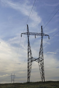 Low angle view of electricity pylon on field against sky