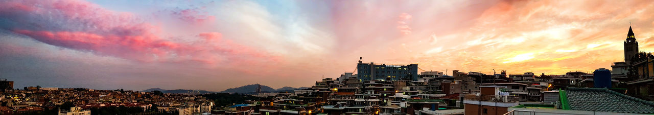 Panoramic view of city against dramatic sky during sunset